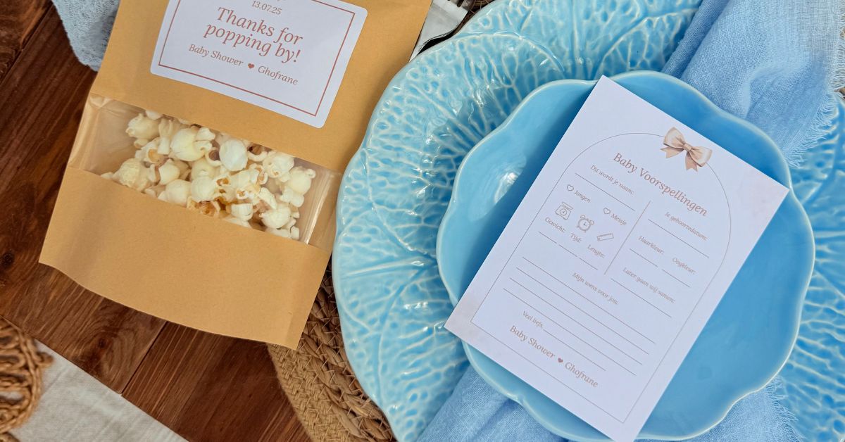 Gedekte babyshower tafel met blauwe borden, popcorn zakjes en invulkaarten